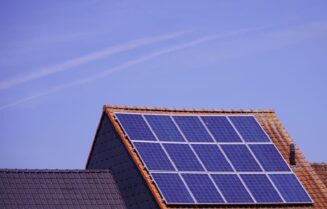 Close-up of solar panels on a tiled rooftop under a clear sky, showcasing renewable energy.