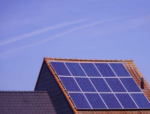 Close-up of solar panels on a tiled rooftop under a clear sky, showcasing renewable energy.