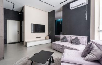 Interior of contemporary spacious living room with comfortable soft couches with cushions and TV set on wall