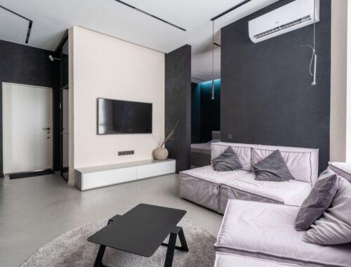Interior of contemporary spacious living room with comfortable soft couches with cushions and TV set on wall
