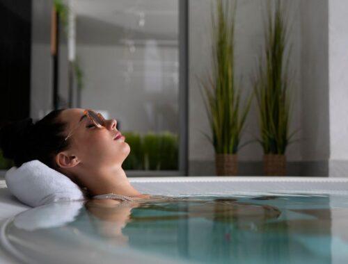 A woman relaxes in a jacuzzi with sunglasses, embodying self-care and relaxation.