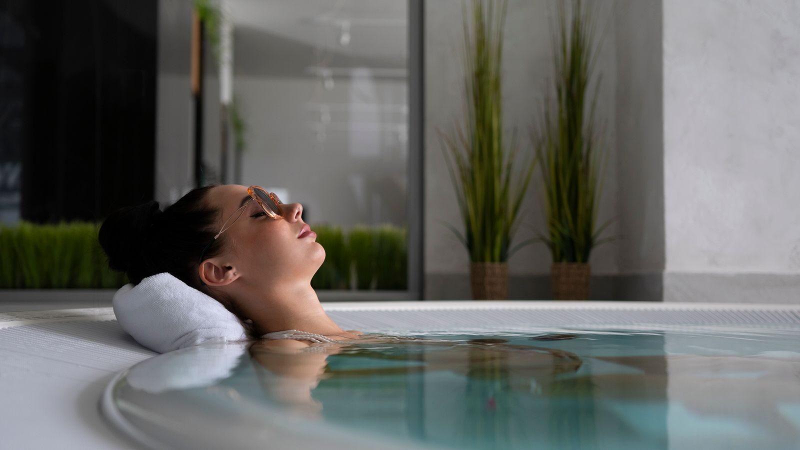 A woman relaxes in a jacuzzi with sunglasses, embodying self-care and relaxation.